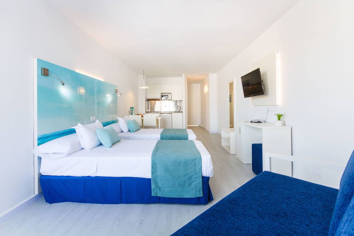 Et moderne hotelværelse med en stor seng, et skrivebord og et tekøkken.
