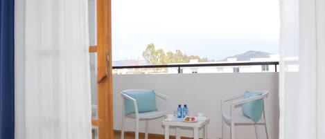 Un balcón con dos sillas blancas, una mesita y vista al mar.