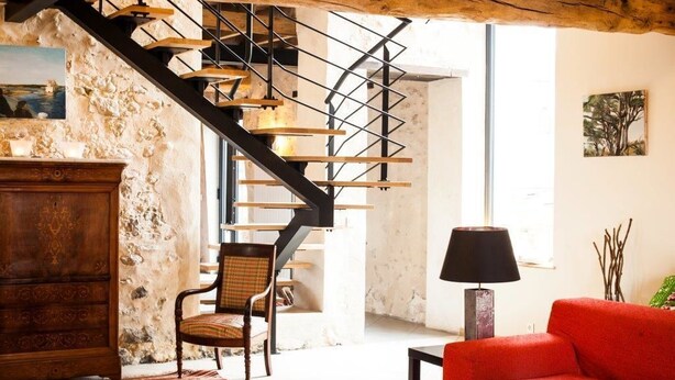 A rustic interior with a wooden staircase, a red sofa, and a wooden cabinet.