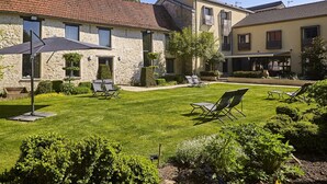 A courtyard with stone buildings, a well-maintained lawn, and outdoor seating.