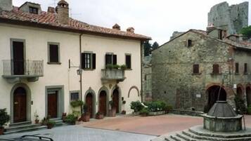 A traditional European street with a building featuring arched windows and a stone facade.