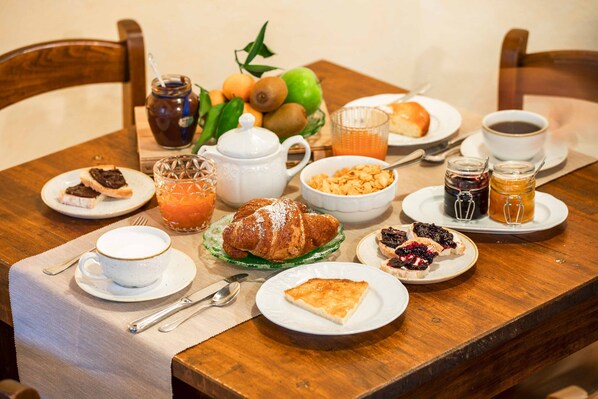 A breakfast table with croissants, pastries, fruit, and beverages. - Locanda Antico Borgo (Civitella in Val di Chiana)