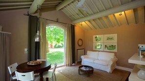 Una sala de estar acogedora con un sofá blanco, una mesa de centro de madera y un comedor con mesa y sillas de madera.