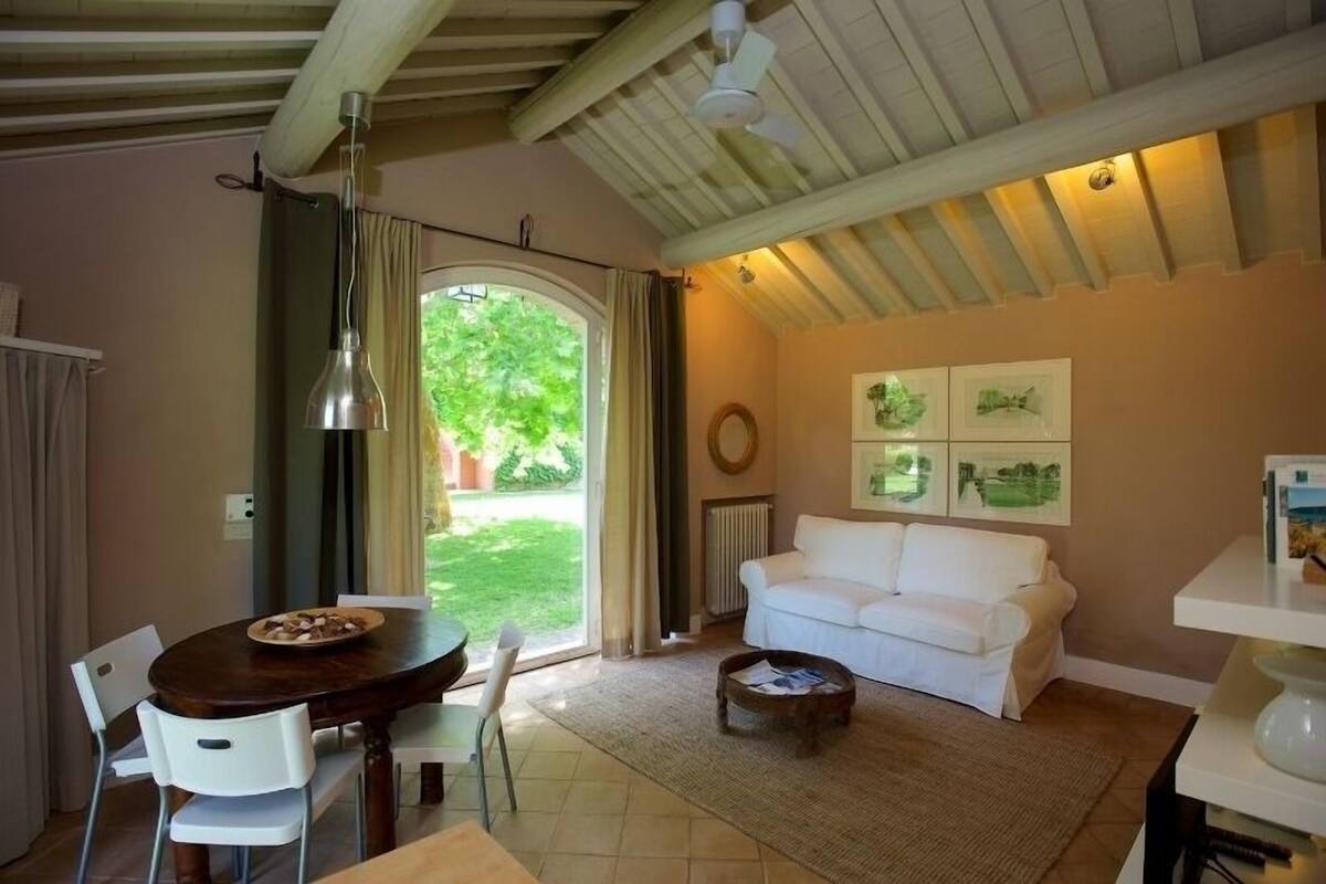 Un salon chaleureux avec un canapé blanc, une table basse en bois et un coin repas comprenant une table et des chaises en bois.