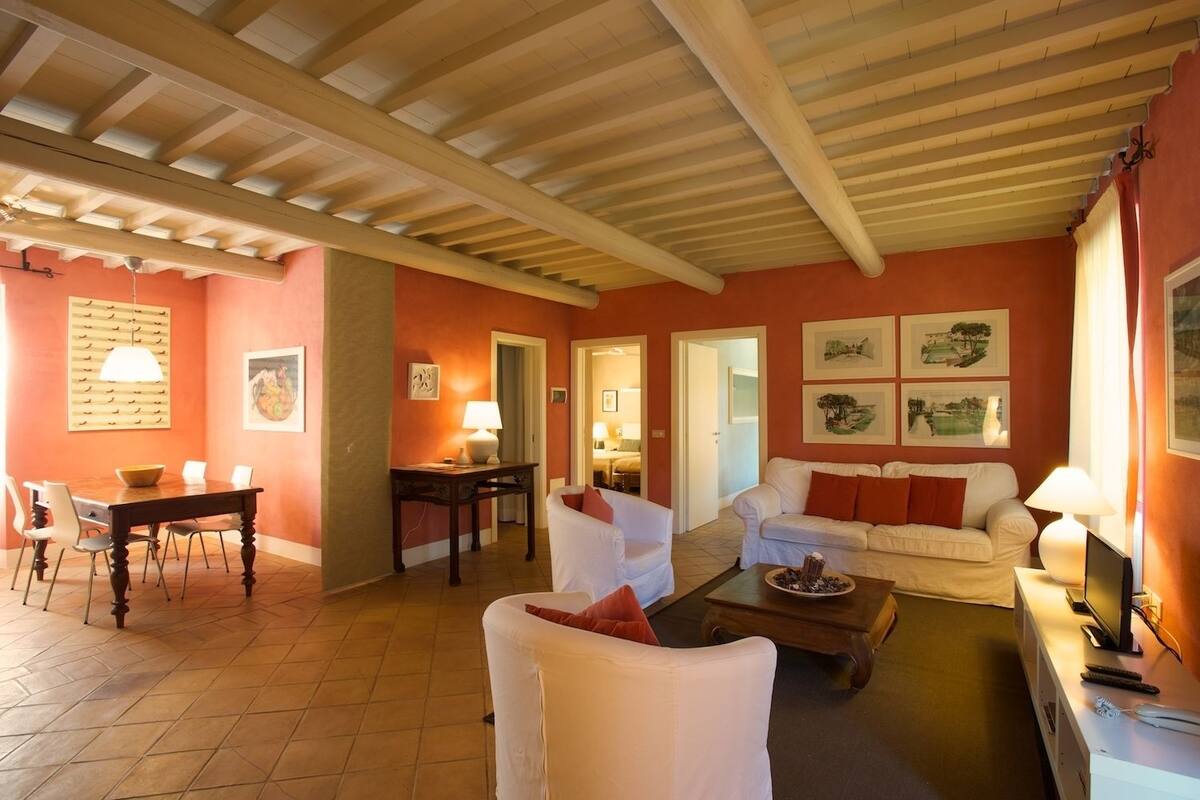 Un vaste salon doté d’un plafond en bois, un coin repas avec une table et des chaises, et un espace détente avec un canapé et des fauteuils.