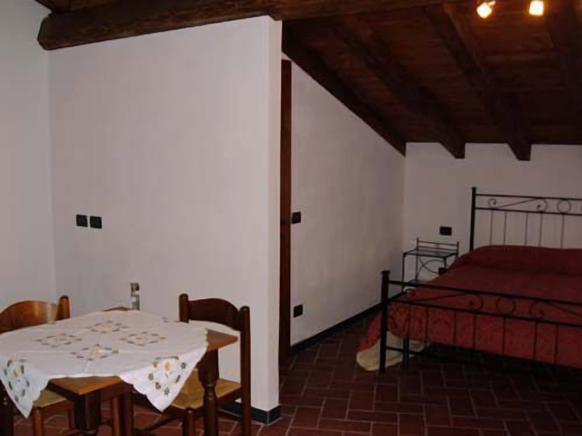Una habitación con una cama, una mesa con sillas y piso de baldosas.