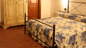 Un dormitorio con techo de madera, una cama con colcha estampada, un armario y una mesita de noche.