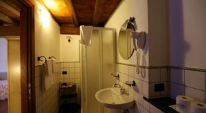 Un baño estrecho con lavamanos, espejo y teléfono.