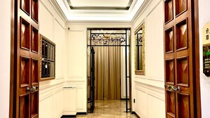 A hallway with marble flooring, wooden doors with glass panels, and a decorative iron gate at the end. - Piazza di Spagna Prestige (Rome)