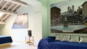 A room with a blue sofa, a painting of a fountain, and a small table with a speaker. - Piazza di Spagna Prestige (Rome)