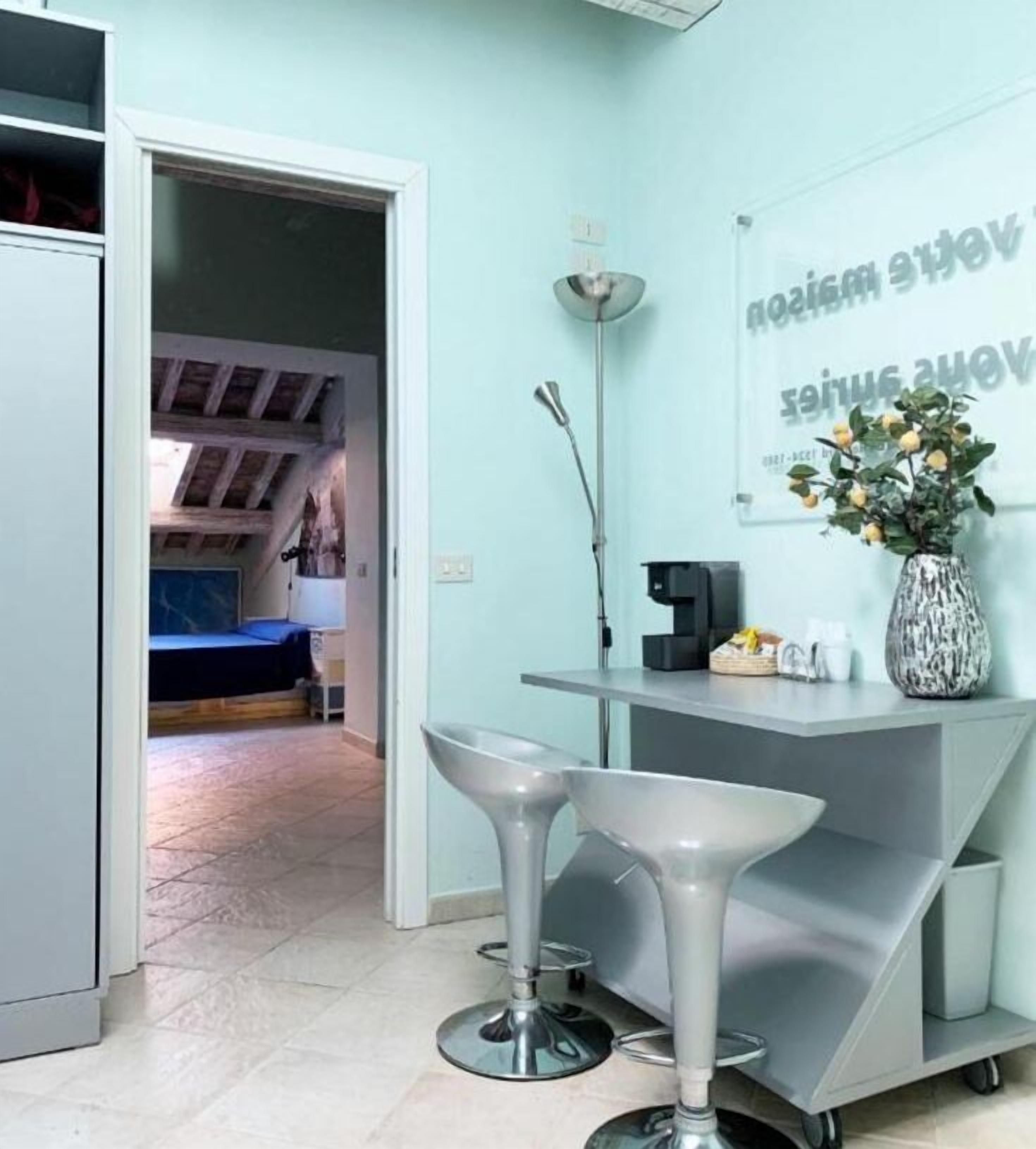 A modern room with a kitchenette, a bar area with stools, and a wall-mounted sign.