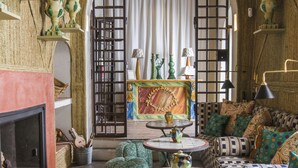 A cozy living room with a fireplace, a sofa set, a coffee table, and a decorative archway. - Posada La Sacristía (Tarifa)