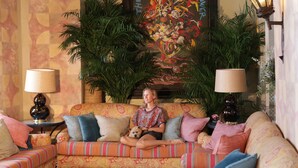 A cozy living room with a sofa, two lamps, and a large floral painting on the wall. - Posada La Sacristía (Tarifa)