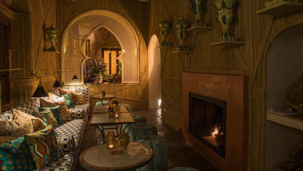 A cozy lounge area with patterned sofas, a fireplace, and decorative vases. - Posada La Sacristía (Tarifa)