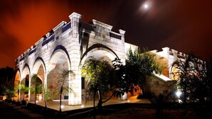 A historic building with arched structures and stone walls, illuminated by artificial lighting at night. - Relais Villa Lucia (Carovigno)