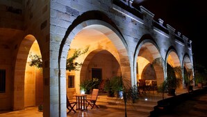 A stone building with multiple arches and a courtyard with seating and potted plants. - Relais Villa Lucia (Carovigno)