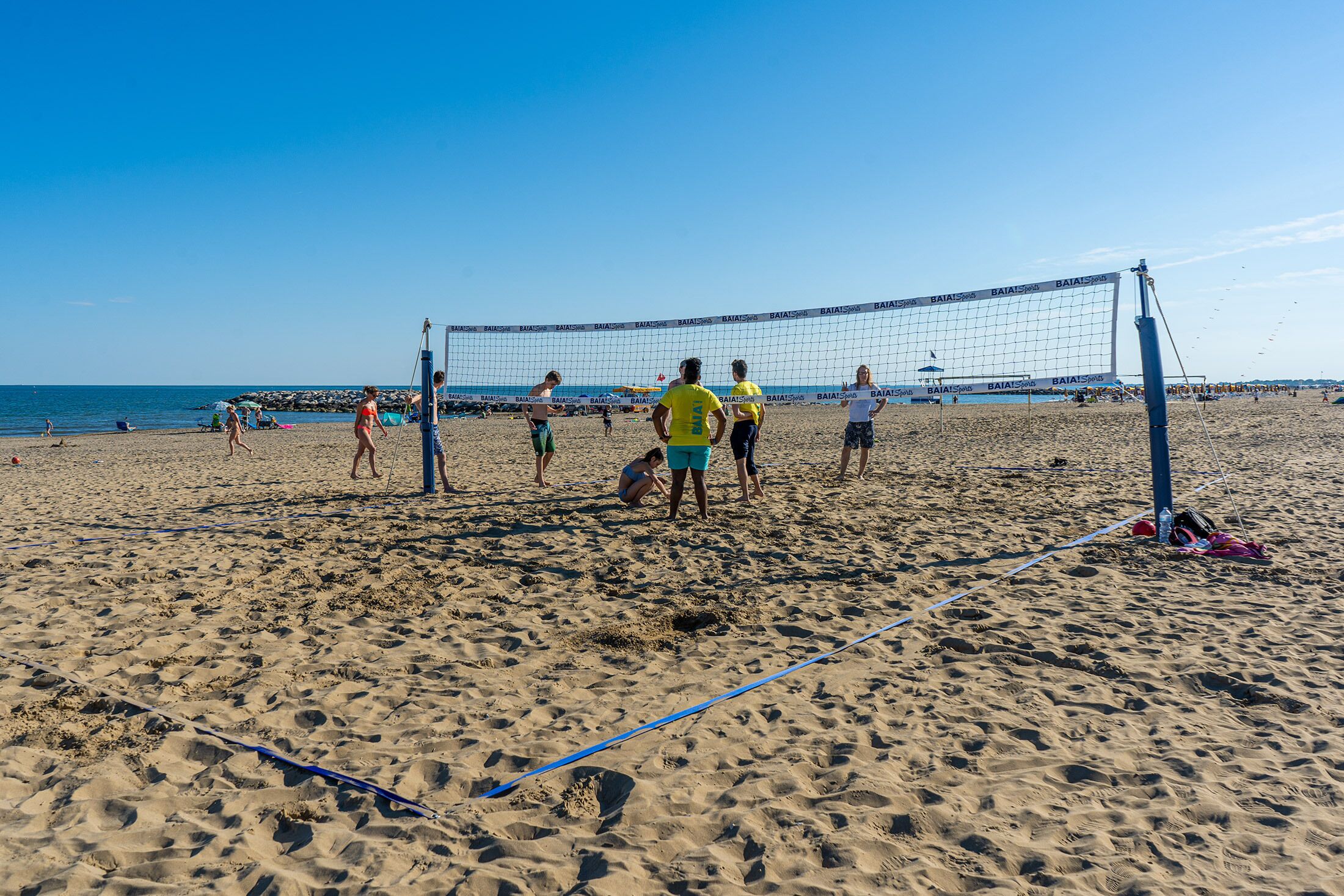 Un partido de voleibol de playa en una arena con cielo despejado.