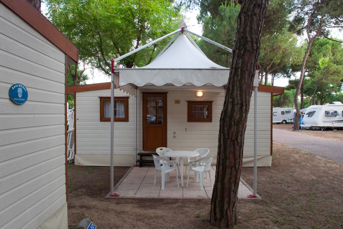 Una construcción pequeña de un solo piso con un patio cubierto, una puerta y una ventana.