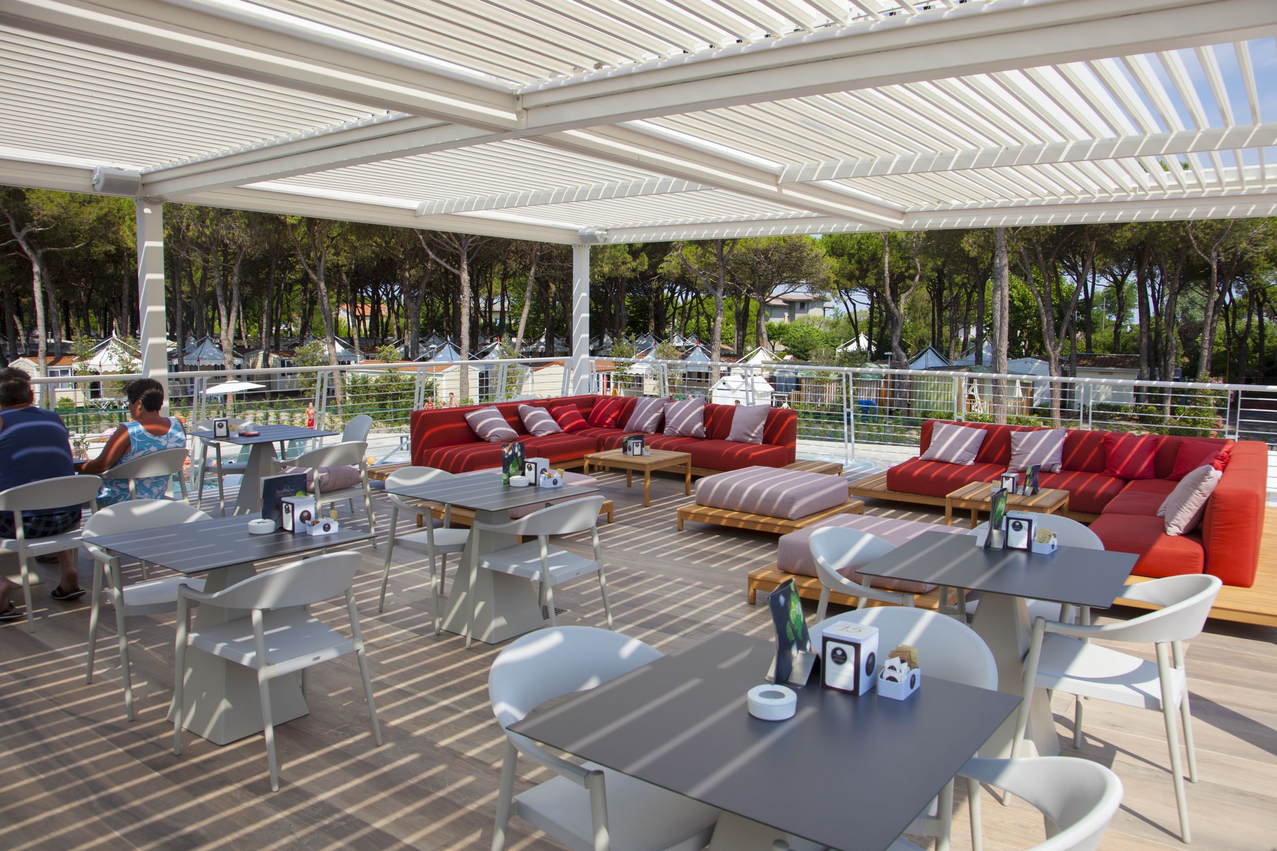 An outdoor patio area with white furniture, red sofas, and tables.
