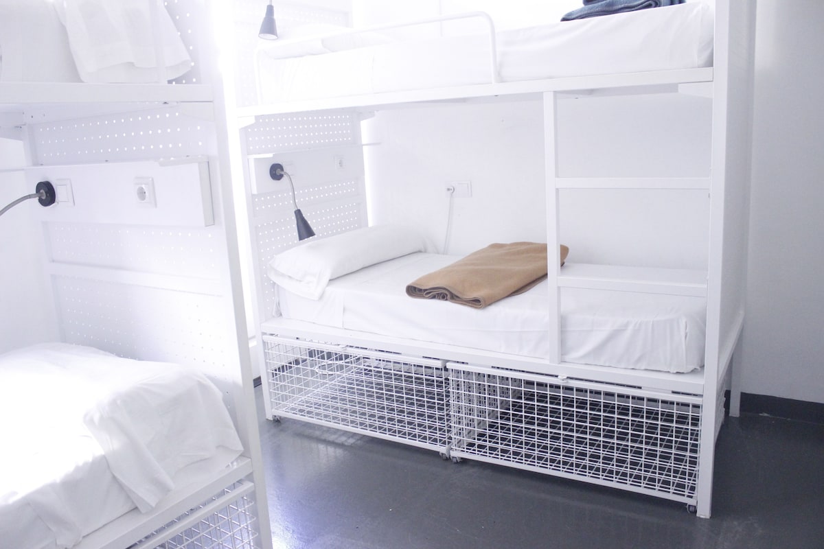 A bunk bed with white bedding and a brown blanket on the top bunk.