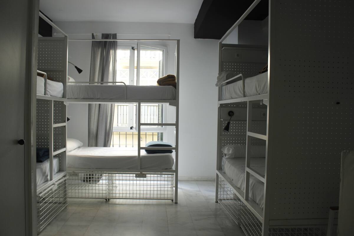 A bunk bed room with a window, metal shelves, and a door.