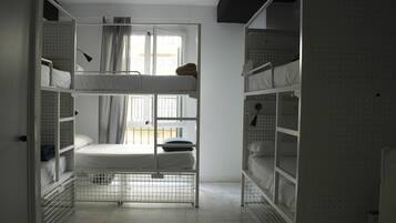 A bunk bed room with a window, metal shelves, and a door.