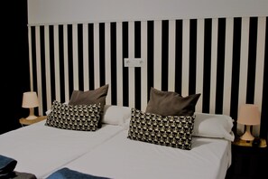 A bed with a black and white striped headboard, two bedside lamps, and patterned pillows. - Feel Hostels Soho Malaga (Málaga)