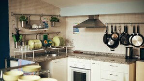 Una cocina con armarios blancos, un horno de acero inoxidable y diferentes utensilios de cocina y vajilla en la pared y la encimera.