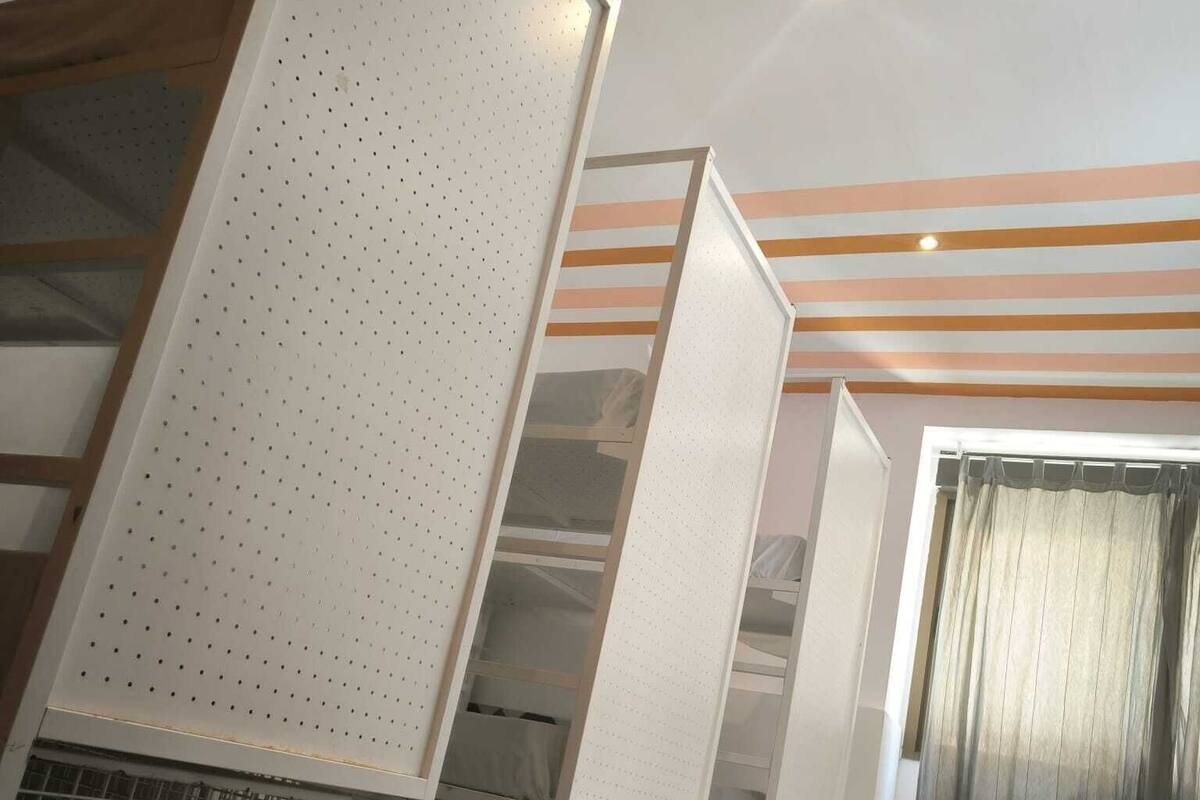 A room with a geometric patterned floor, white shelving units with perforated panels, and a striped ceiling.