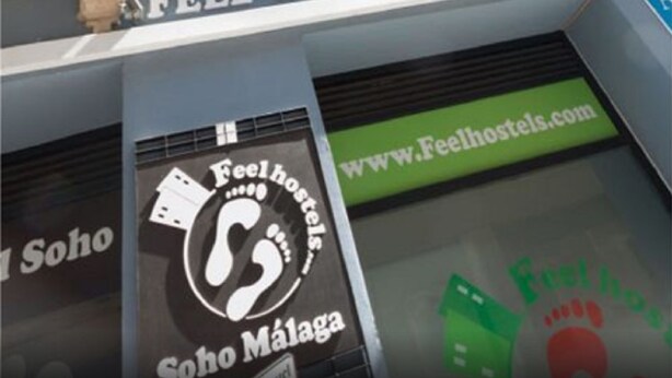 Un cartel de hotel con el nombre 'Feel Hostels Soho Málaga' y la dirección web 'www.feelhostels.com'.