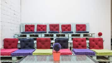 A room with a glass table in the center, surrounded by sofas with various colored cushions.