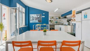 Una cocina moderna con armarios blancos, una isla central y sillas color naranja.