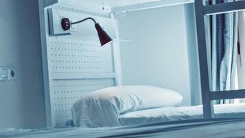 A bunk bed with a white headboard, a red desk lamp, and a white pillow.