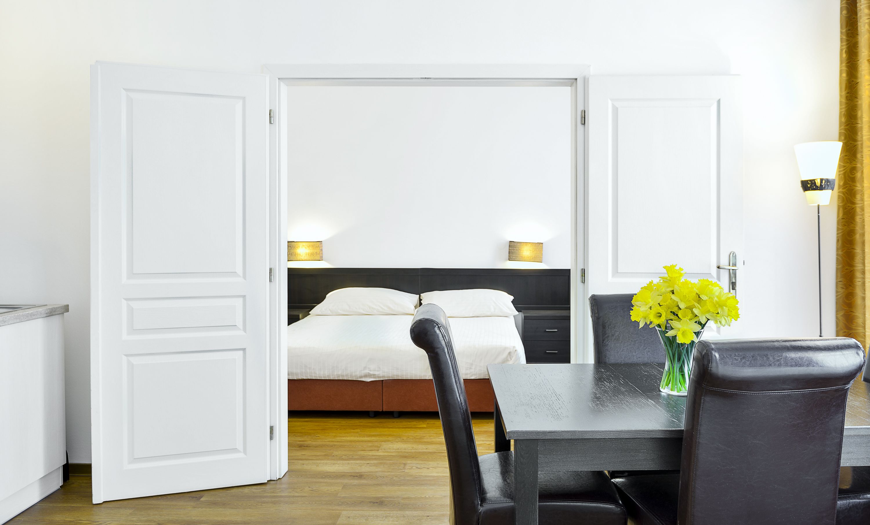 A hotel room with a bed, bedside lamps, a dining table, and a chair.