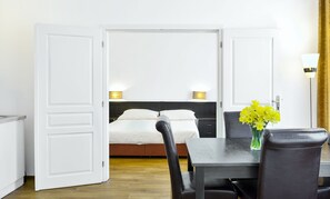 Una habitación de hotel con cama, lámparas de noche, una mesa de comedor y una silla.