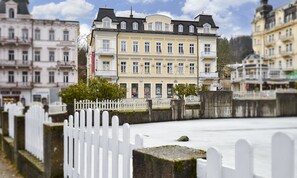 A multi-story building with a yellow facade, white trim, and a balcony. - Apartments Central Park Marienbad (Marianske Lazne)