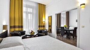 Hotelkamer met een groot bed, een bureau met stoel, een spiegel en uitzicht op een eetruimte.