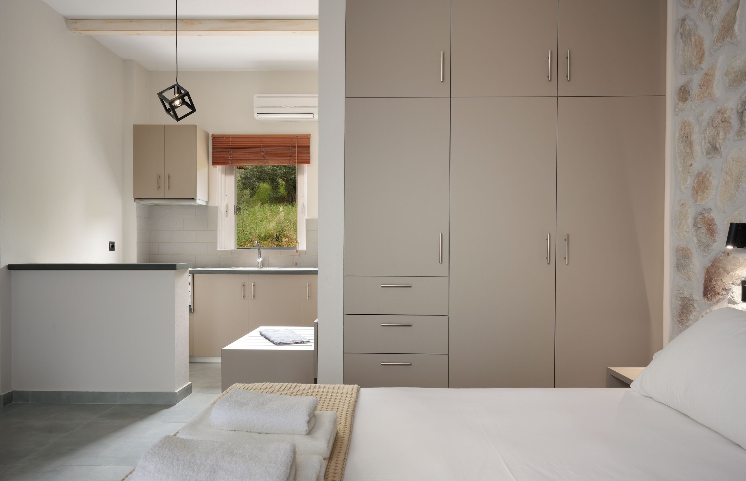 Une chambre à coucher avec un lit, une table de chevet et une armoire. Il y a une fenêtre qui donne sur un paysage verdoyant.