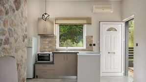 Una cocina moderna con pared de piedra, horno empotrado y ventana con persianas.