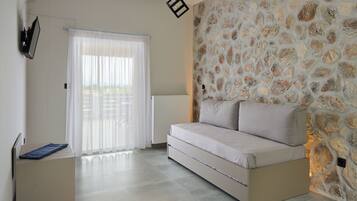 A modern bedroom with a stone wall, a sofa bed, a radiator, and a window with curtains.