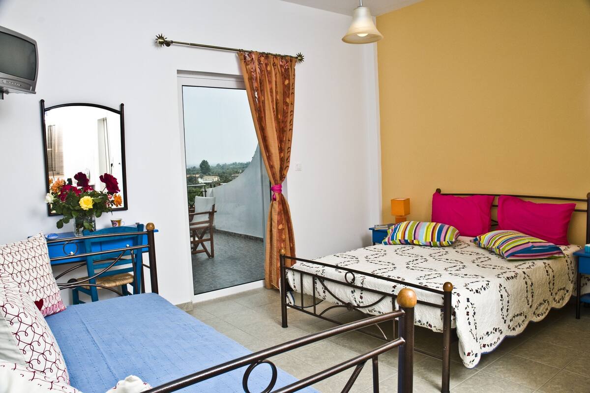 A bedroom with a bed, a desk, a chair, a wardrobe, and a window with curtains.