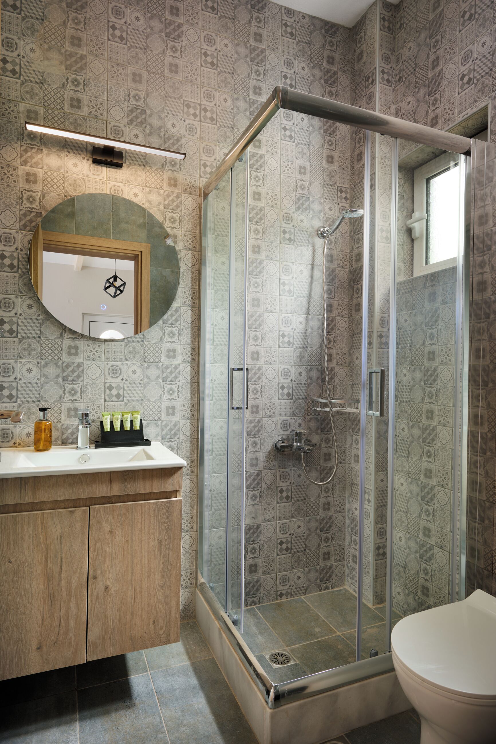 Un bagno con doccia, lavandino, WC e specchio.