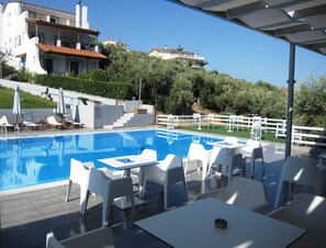 Una piscina al aire libre de temporada, sillones reclinables de piscina