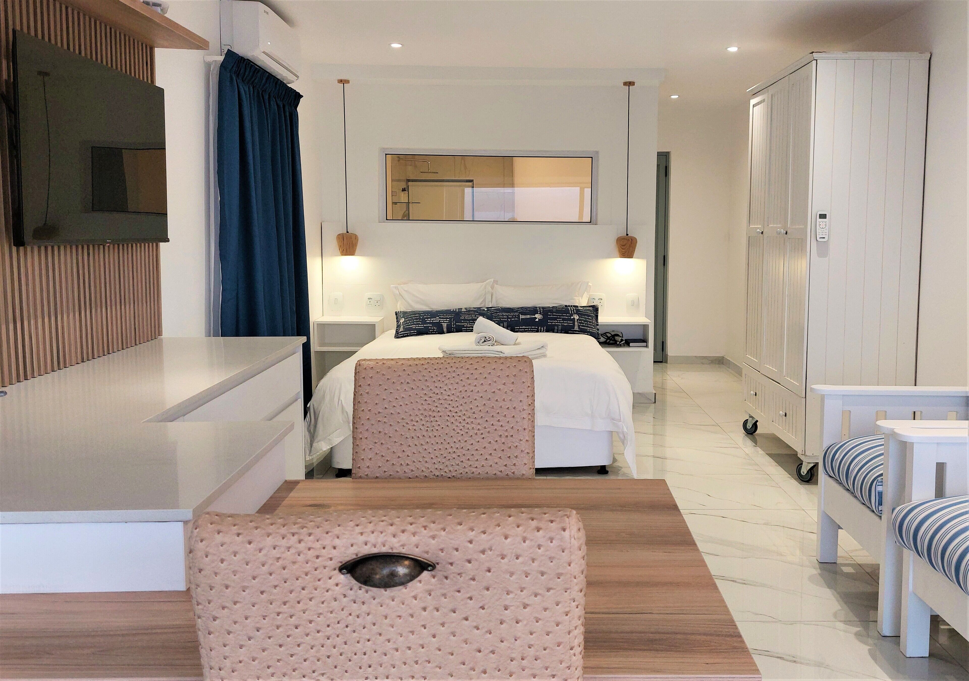 Una habitación de hotel moderna con cama, mesitas de noche, televisor y armario.