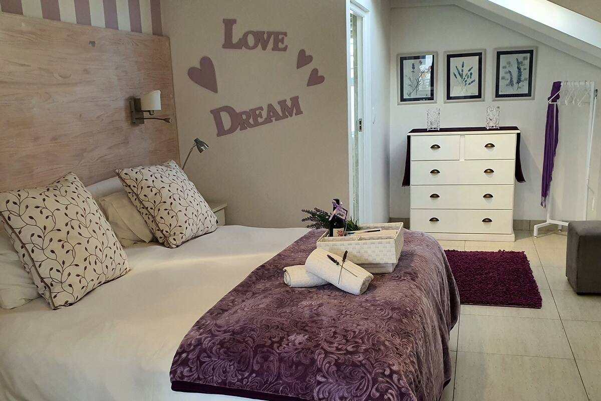 A bedroom with a bed, pillows, a dresser, a wall with 'Love Dream' text, and framed pictures on the wall.