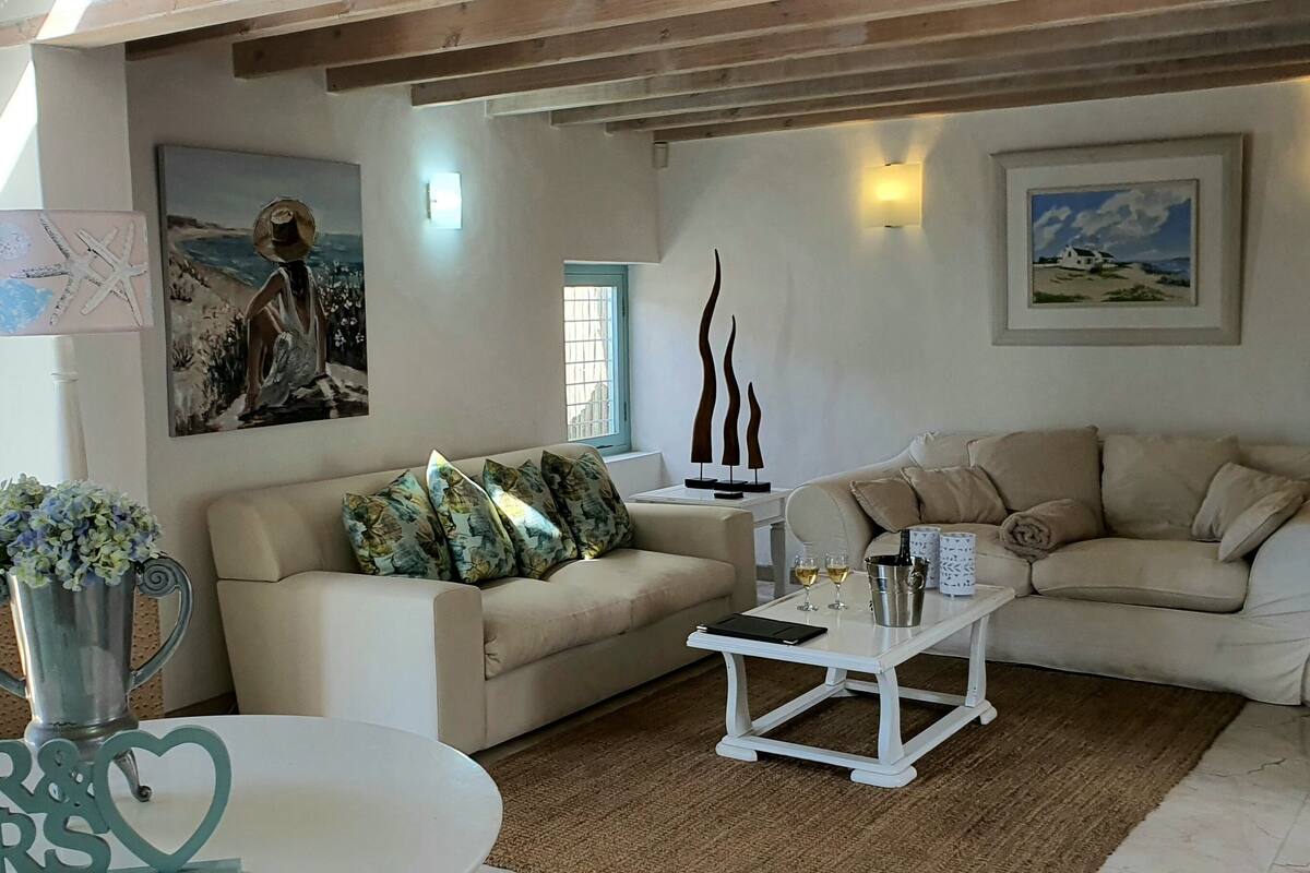 A living room with two sofas, a coffee table, a grill outside the window, and artwork on the walls.