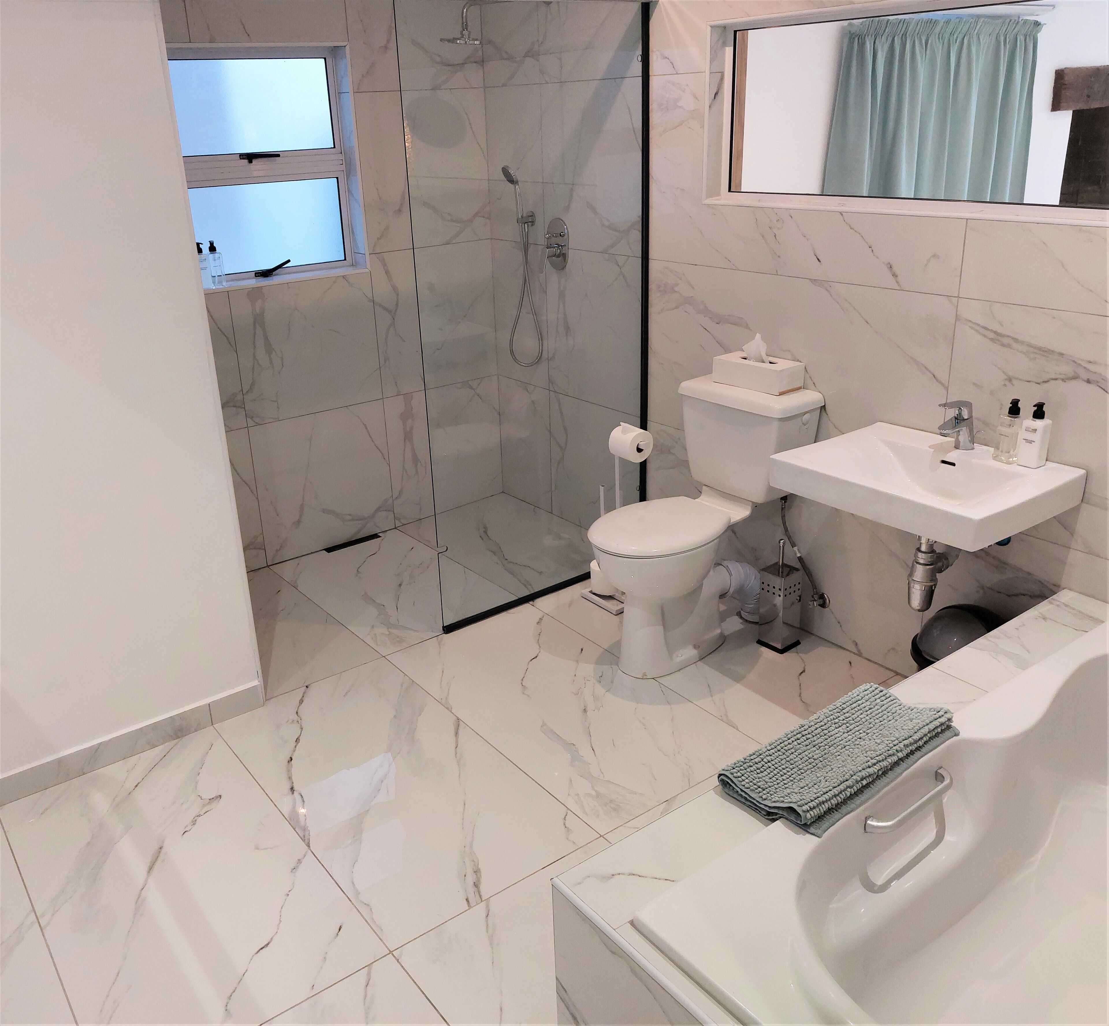 A modern bathroom with a toilet, sink, and shower.
