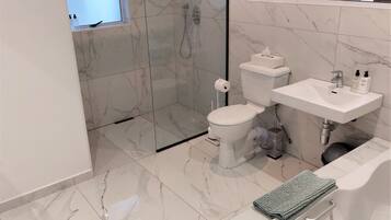 A modern bathroom with a toilet, sink, and shower.