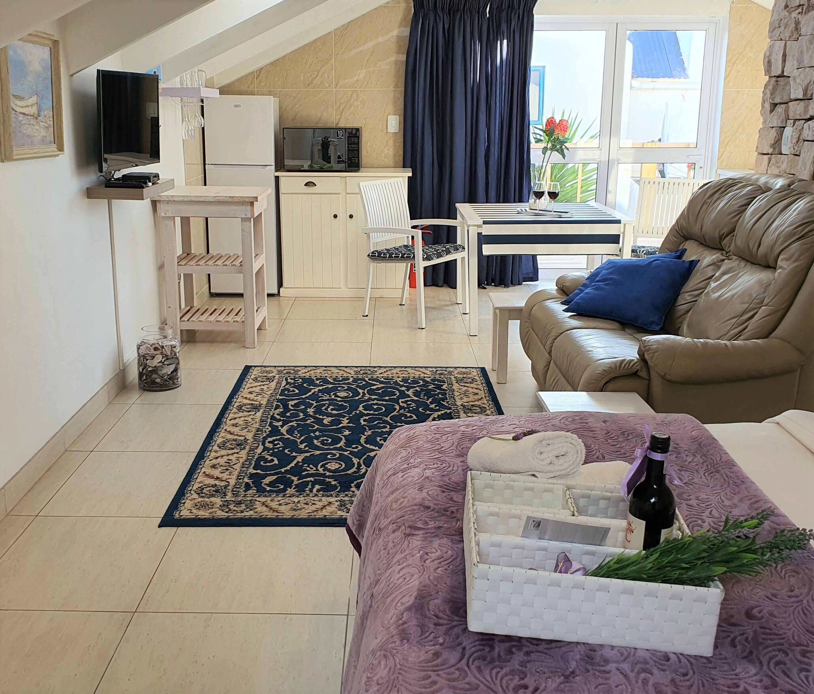 Ett kompakt bostadsutrymme med ett litet kök, en soffa, ett matbord och en TV som är monterad på väggen.
