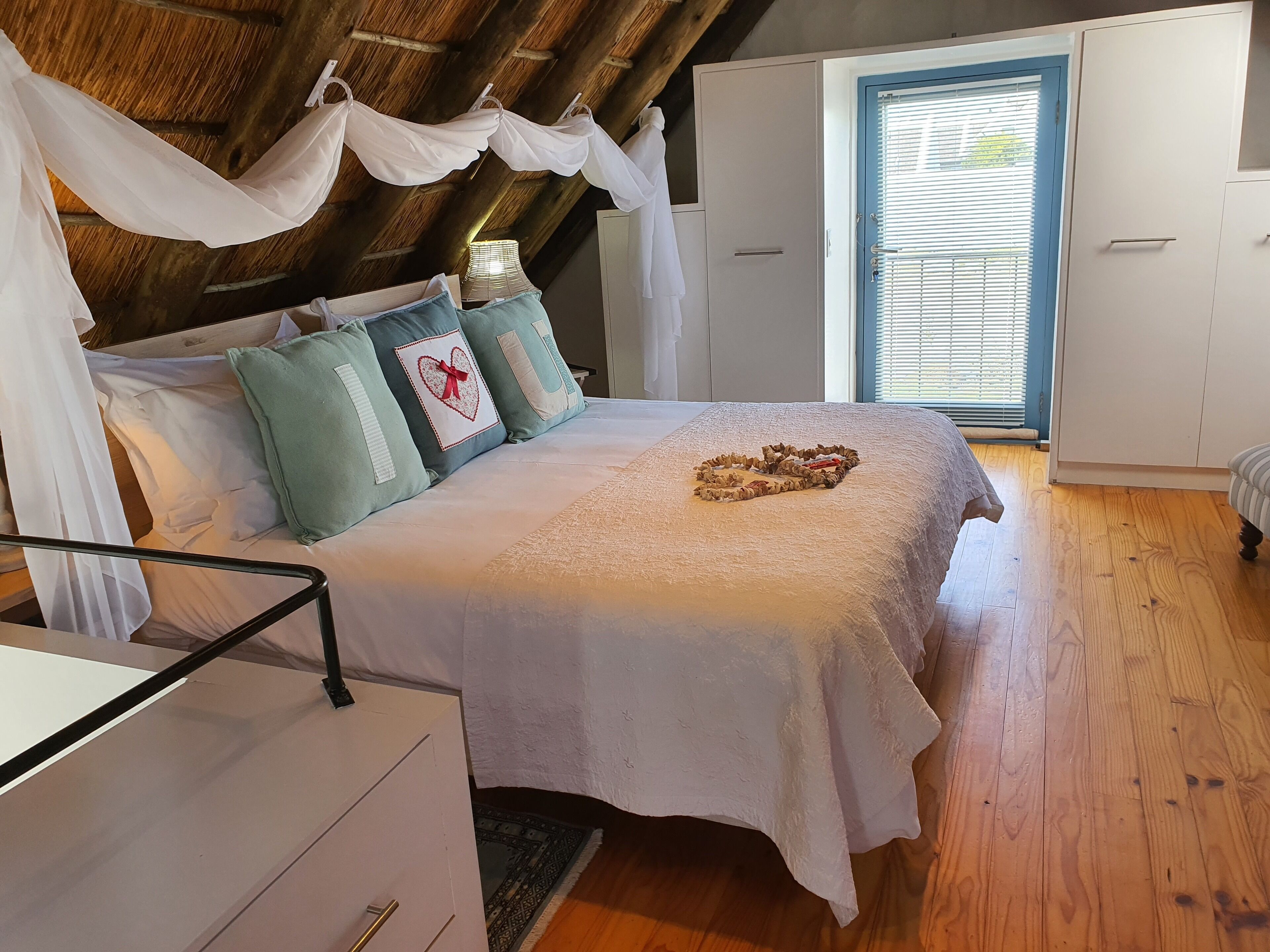 A bedroom with a bed, white wardrobe, and a window with blinds.